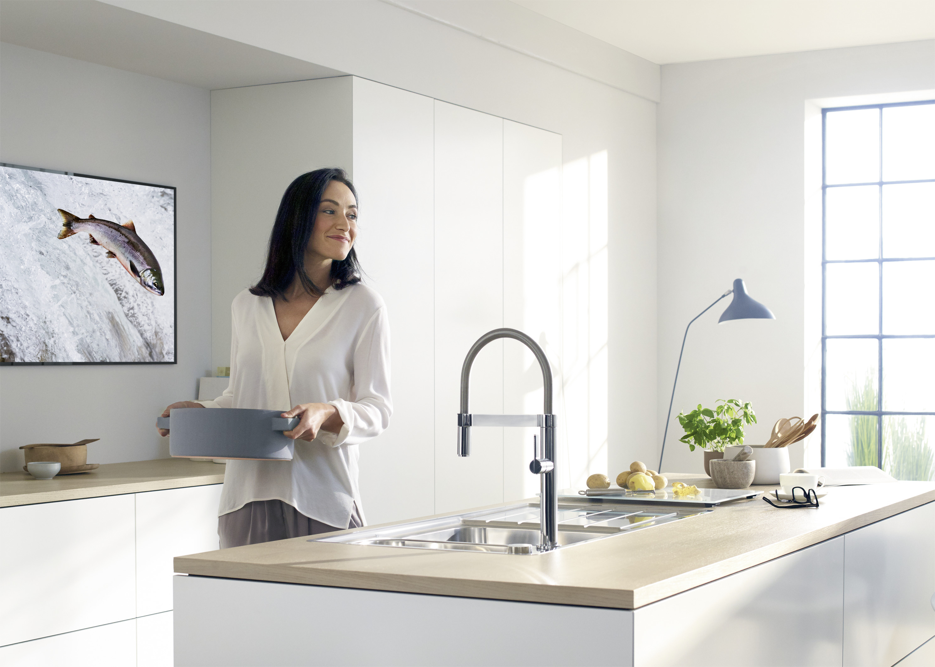 A woman stands in front of a BLANCO sink and has a saucepan in her hand